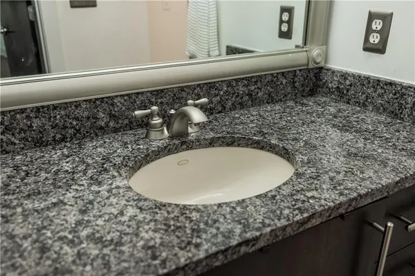 a bathroom with a granite countertop sink and a mirror
