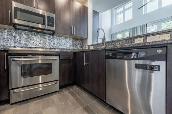 a kitchen with stainless steel appliances granite countertop a stove microwave and refrigerator