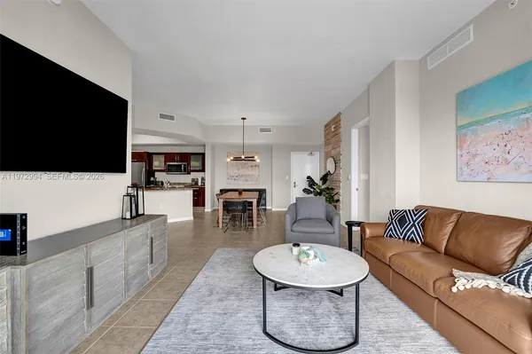 a living room with furniture a flat screen tv and kitchen view