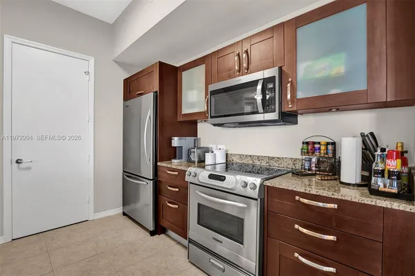 a kitchen with stainless steel appliances granite countertop a refrigerator a stove a sink a dining table and chairs