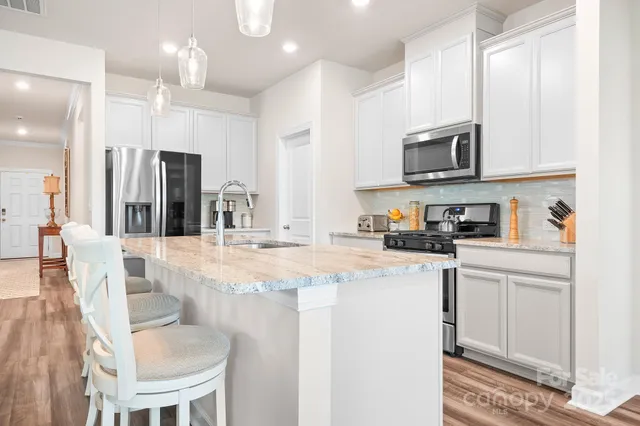 a dining room with wooden floor a chandelier a wooden table and chairs