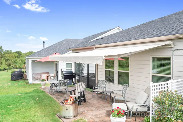 a view of a patio with table and chairs potted plants and floor to ceiling window