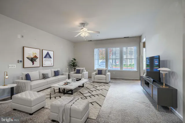 a living room with furniture ceiling fan and a window