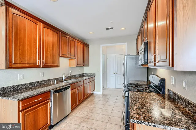 a kitchen with stainless steel appliances granite countertop a stove a sink dishwasher and a refrigerator