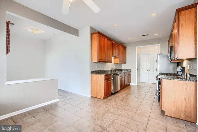 a large kitchen with stainless steel appliances granite countertop a stove a sink and a refrigerator