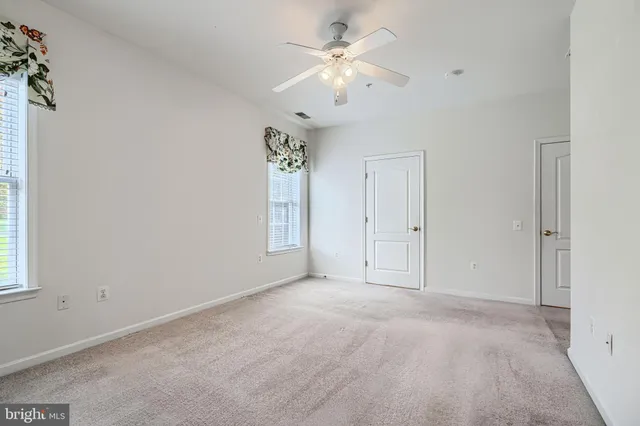 an empty room with windows and fan