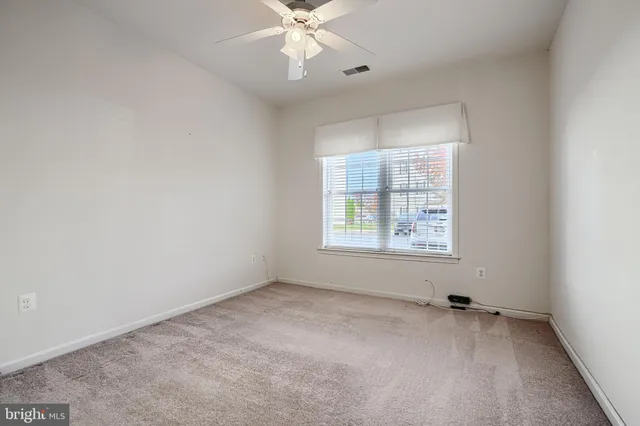 an empty room with a window and a fan