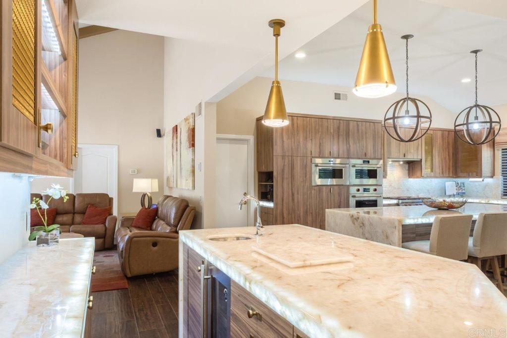 9369 Quail Canyon Road El Cajon, CA 92021 - Photo 8 of 43 a kitchen with stainless steel appliances kitchen island granite countertop a stove a sink dishwasher and white cabinets with wooden floor