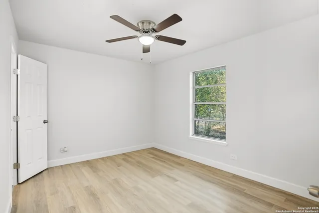 an empty room with a window and a ceiling fan
