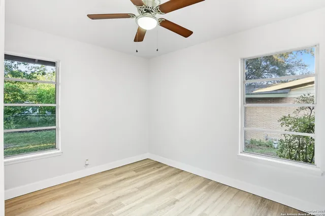an empty room with a window and a fan