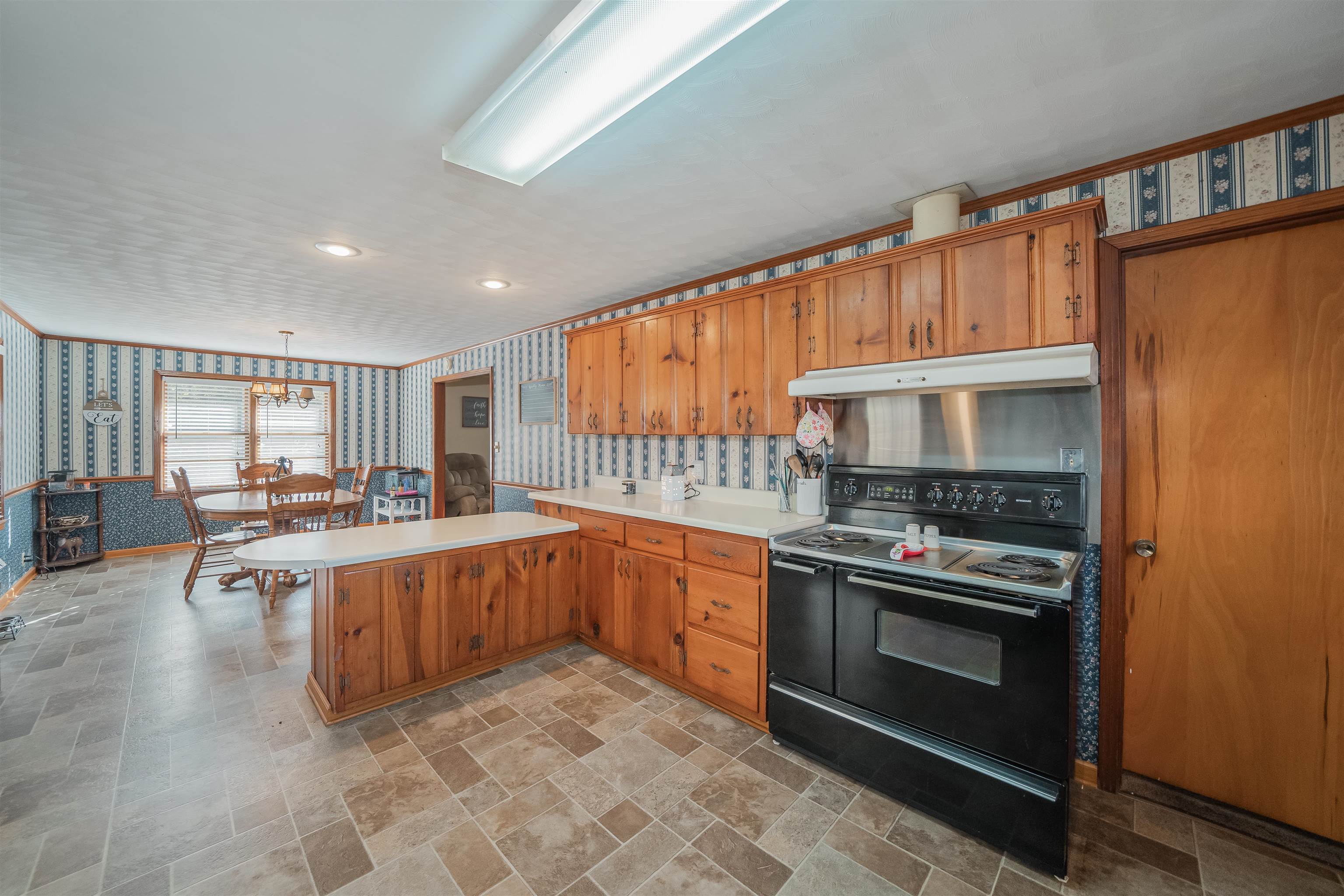 1315 Bishop Road Middleton, TN 38052 - Photo 7 of 31 Kitchen featuring an inviting chandelier, black range with electric cooktop, kitchen peninsula, decorative light fixtures, and exhaust hood