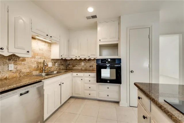 a kitchen with stainless steel appliances granite countertop a sink and dishwasher a stove top oven with white cabinets