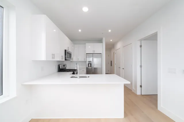 a kitchen with kitchen island a sink stainless steel appliances and white cabinets