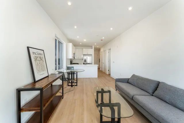 a living room with furniture and a dining table with kitchen view