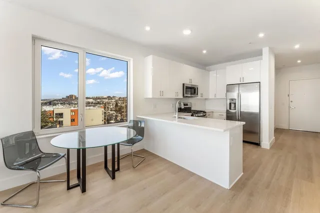 a kitchen with a refrigerator a counter top space and a view of living room