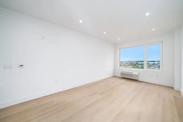 a view of an empty room with a window and wooden floor