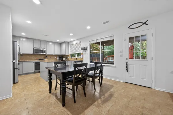 a kitchen with stainless steel appliances kitchen island granite countertop a refrigerator oven a sink dishwasher and white cabinets with wooden floor