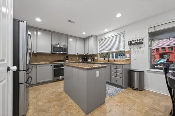a kitchen with granite countertop a sink a window stainless steel appliances and cabinets