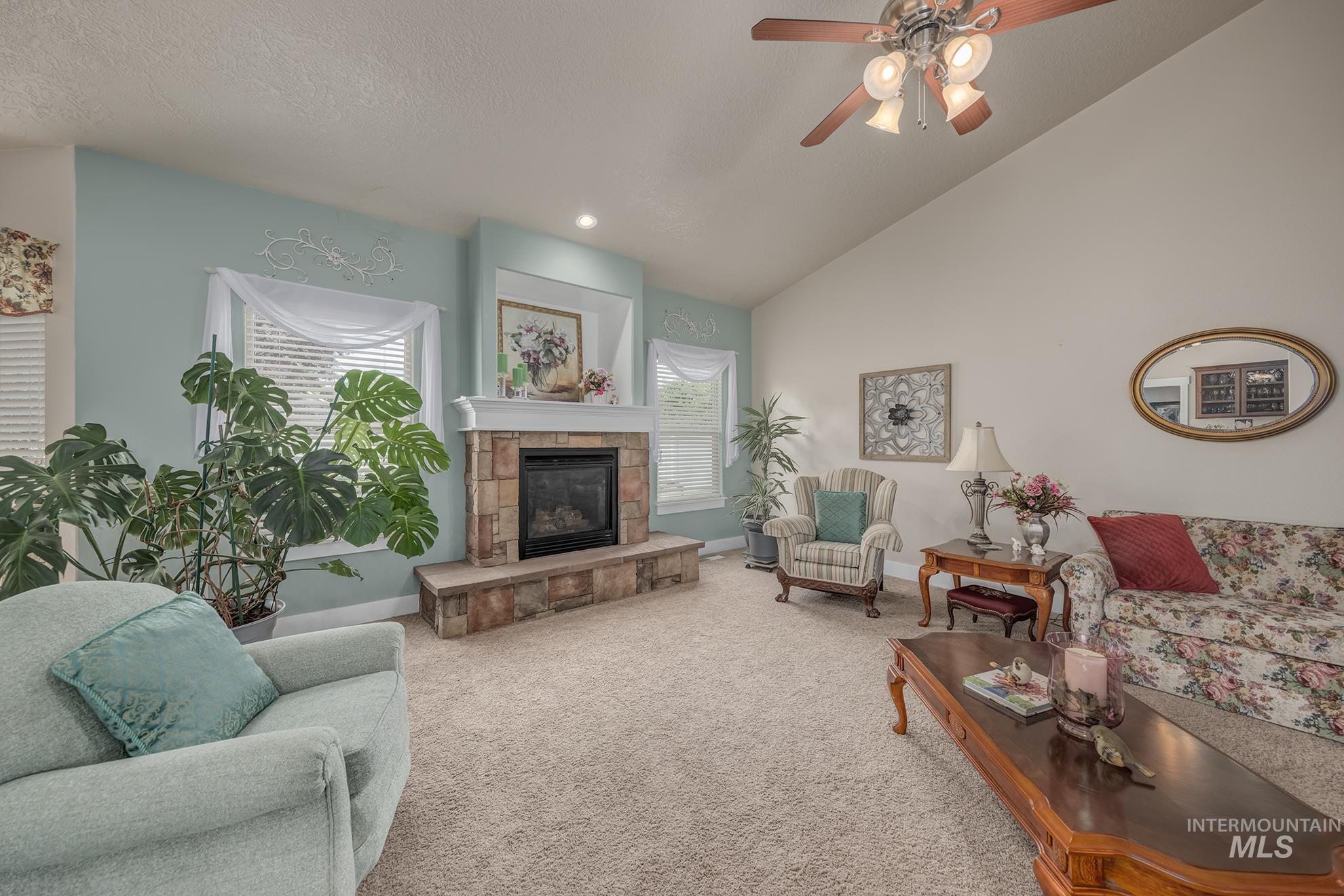 420 West Indianhead Road Weiser, ID 83672 - Photo 7 of 40 Living space featuring a stone-clad fireplace with a white mantle, vaulted ceilings, and light-colored carpeting