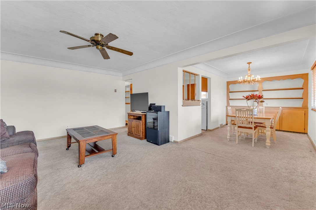 3023 Norris Avenue Cleveland, OH 44134 - Photo 7 of 41 Open-concept living and dining areas featuring neutral-toned carpet flooring, a ceiling fan with integrated lighting, and a chandelier in the dining space