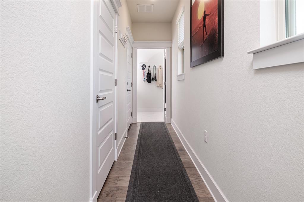 1724 Rowdy Loop Leander, TX 78641 - Photo 15 of 32 Hall with a textured wall and dark wood finished floors left door is power room and laundry at the end of hallway