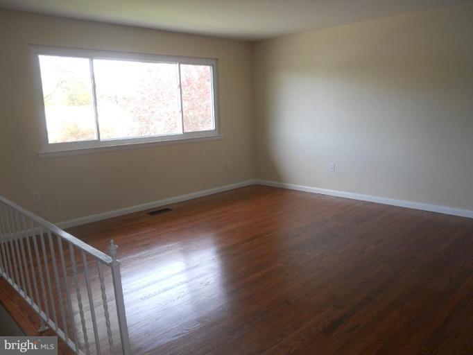 8820 Sigrid Road Randallstown, MD 21133 - Photo 2 of 23 an empty room with wooden floor and windows
