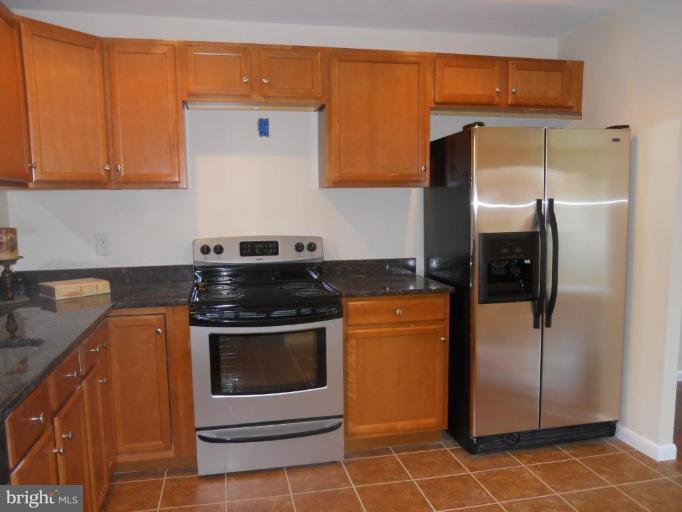 8820 Sigrid Road Randallstown, MD 21133 - Photo 5 of 23 a kitchen with stainless steel appliances granite countertop a refrigerator a stove and a sink with wooden cabinets