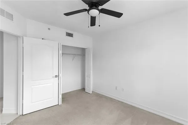 an empty room with a ceiling fan and carpet
