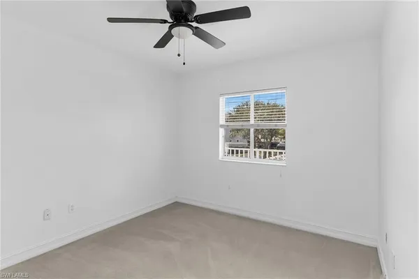 an empty room with a window and a fan