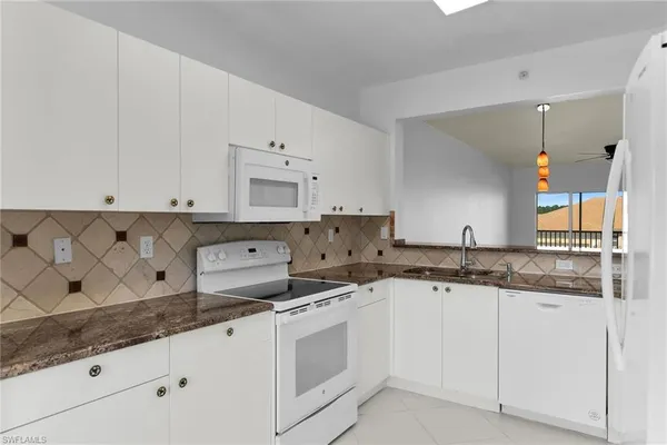 a kitchen with granite countertop white cabinets and white appliances