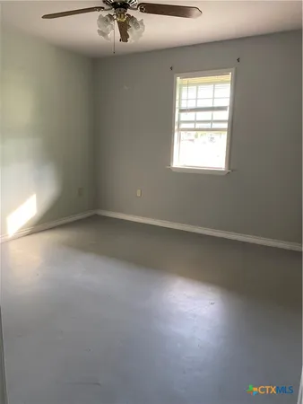 an empty room with a window and a ceiling fan