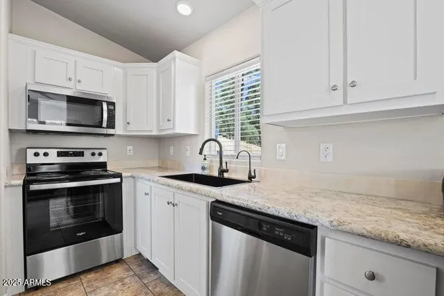 a kitchen with granite countertop white cabinets and stainless steel appliances