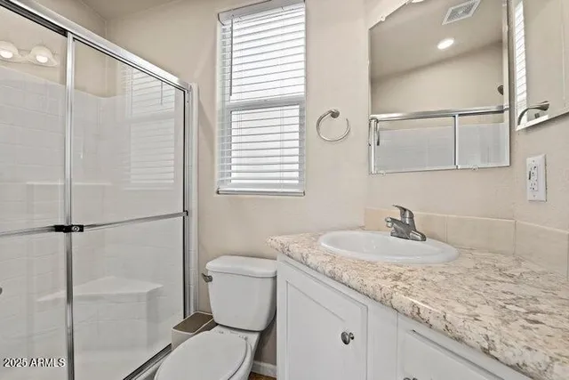 a bathroom with a granite countertop sink mirror vanity and toilet