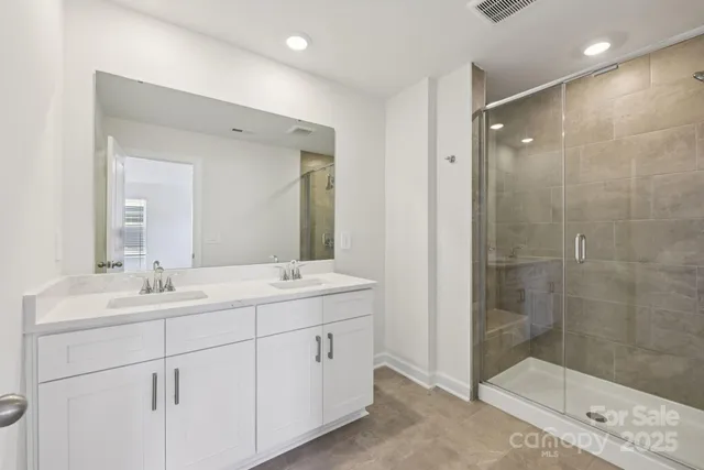 a bathroom with a double vanity sink mirror and shower