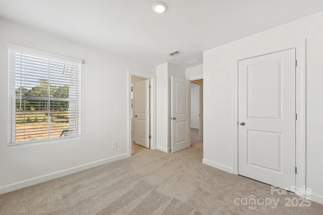 a view of an empty room with window and closet area