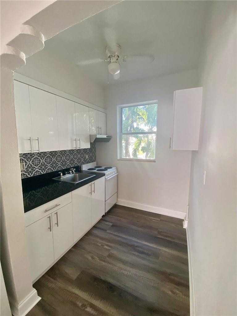 320 80th Street, Unit 15 Miami Beach, FL 33141 - Photo 5 of 18 a kitchen with granite countertop a stove and a white cabinets
