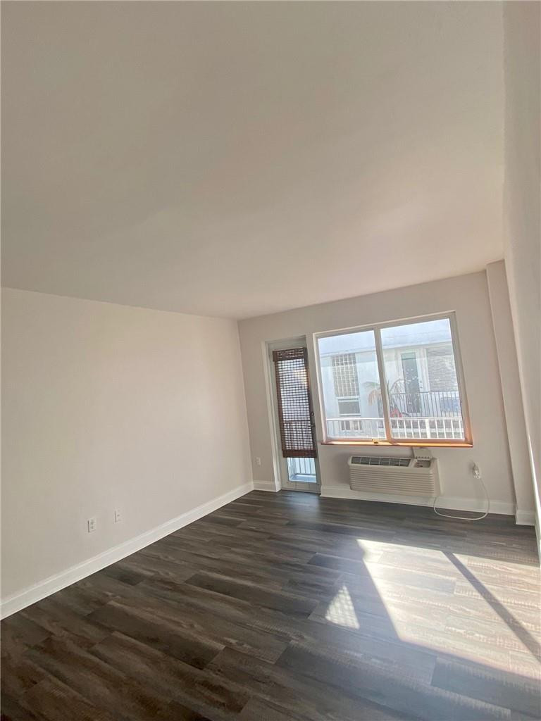 320 80th Street, Unit 15 Miami Beach, FL 33141 - Photo 7 of 18 an empty room with wooden floor and windows