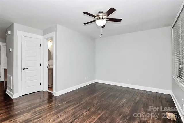 an empty room with wooden floor and a ceiling fan