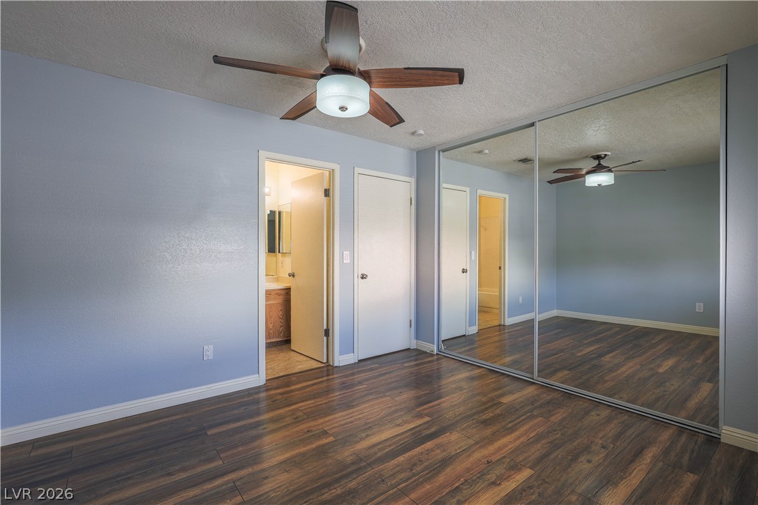 6750 Del Rey Avenue, Unit 267 Las Vegas, NV 89146 - Photo 4 of 20 Well-lit primary bedroom featuring a ceiling fan, lustrous hardwood-style flooring, and mirrored closet doors.
