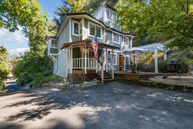 a view of a white house with large trees and wooden fence