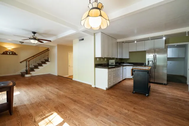 a large kitchen with granite countertop a stove top oven a sink dishwasher and a refrigerator with wooden floor