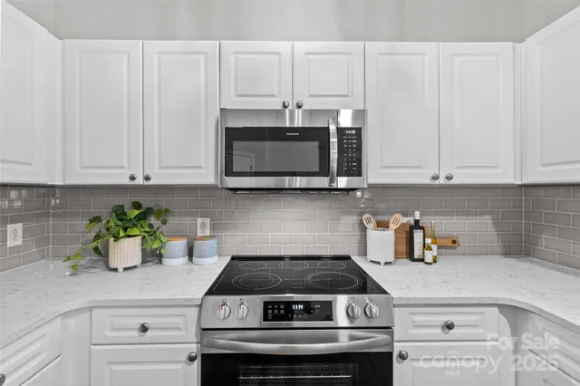a kitchen with stainless steel appliances granite countertop white cabinets a stove a sink and dishwasher