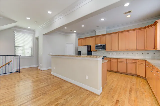 a large kitchen with stainless steel appliances granite countertop a large counter top a sink and a refrigerator