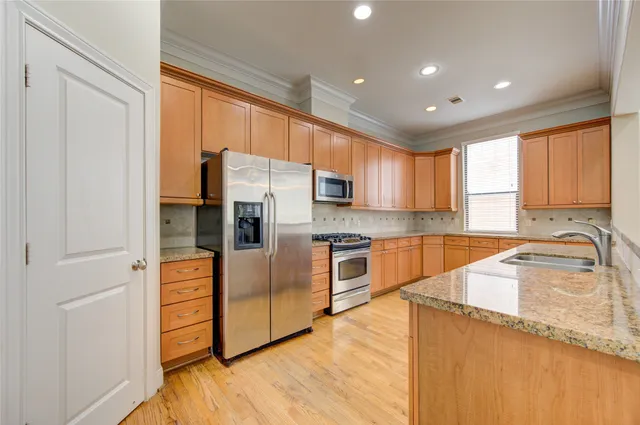 a kitchen with granite countertop a refrigerator a sink dishwasher stove and oven