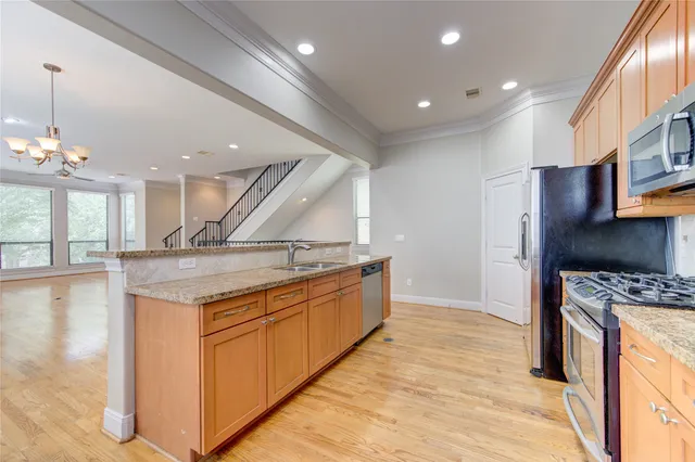 a kitchen with stainless steel appliances granite countertop a sink a stove and a wooden floors