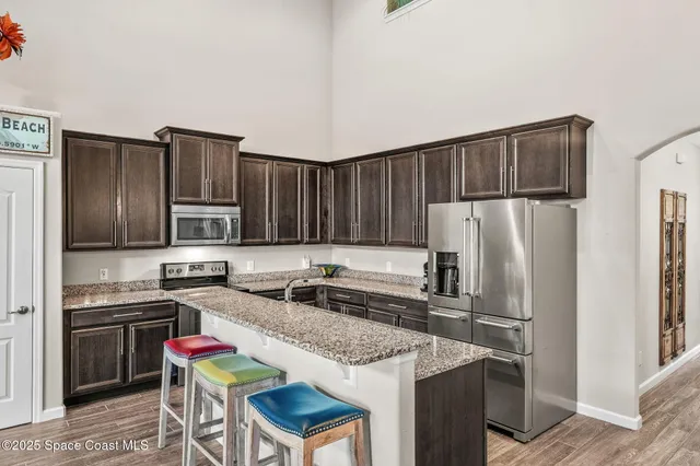 a living room with lots of furniture kitchen view and a chandelier