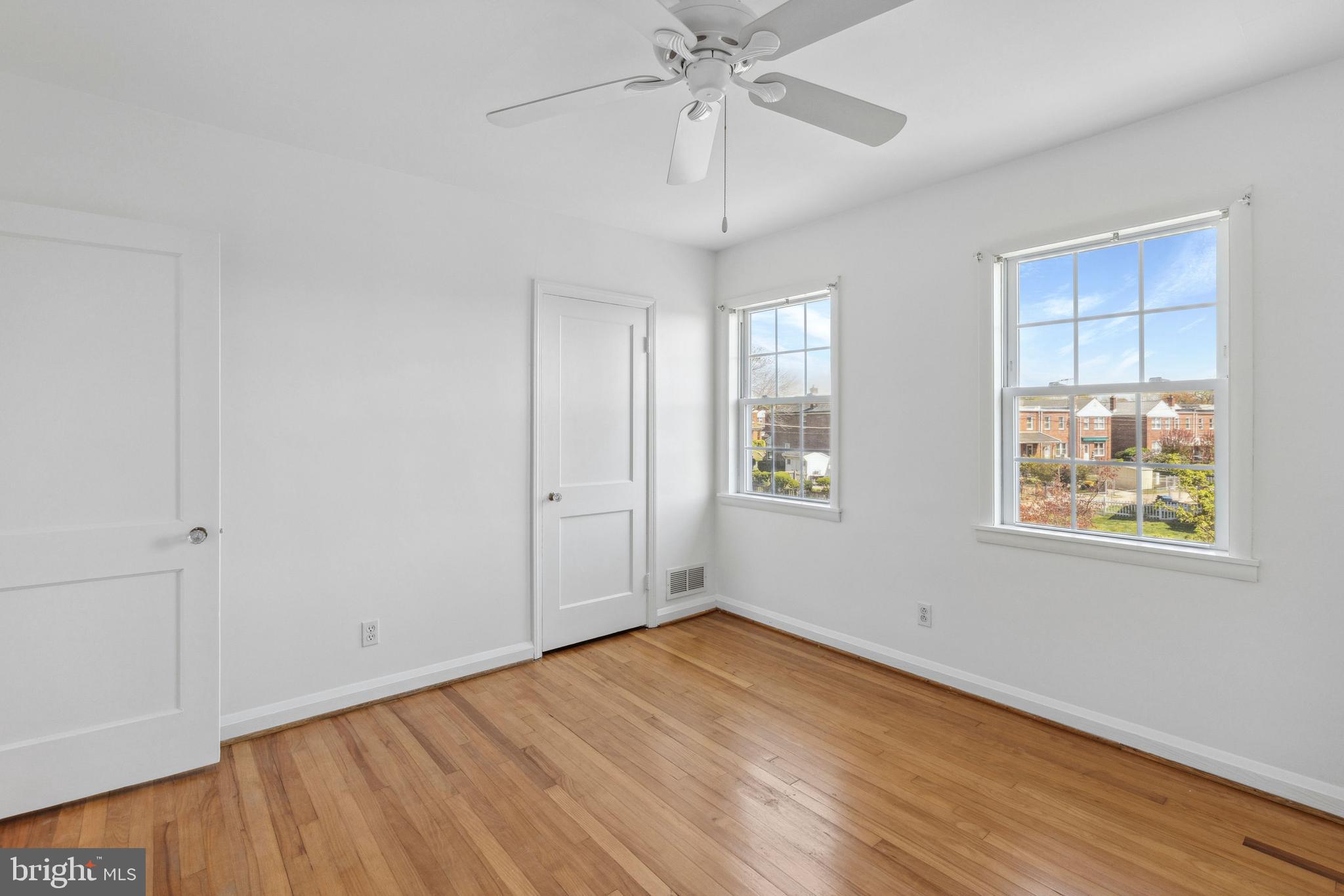 3418 Dunran Road Baltimore, MD 21222 - Photo 9 of 19 an empty room with wooden floor chandelier fan and windows