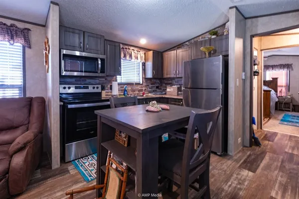 a kitchen with stainless steel appliances a refrigerator a stove a sink a dining table and chairs