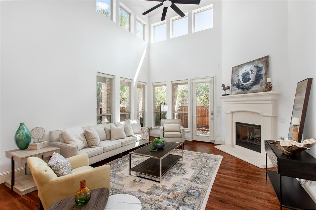 846 Deerfield Road Allen, TX 75013 - Photo 10 of 40 Expansive living area featuring a vaulted ceiling with a ceiling fan, a fireplace with a substantial mantel, multiple windows, and wood-finish flooring