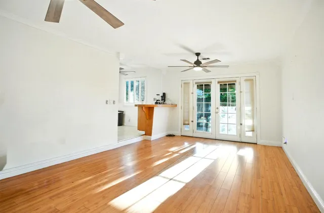 a view of a big room with wooden floor a ceiling fan and windows